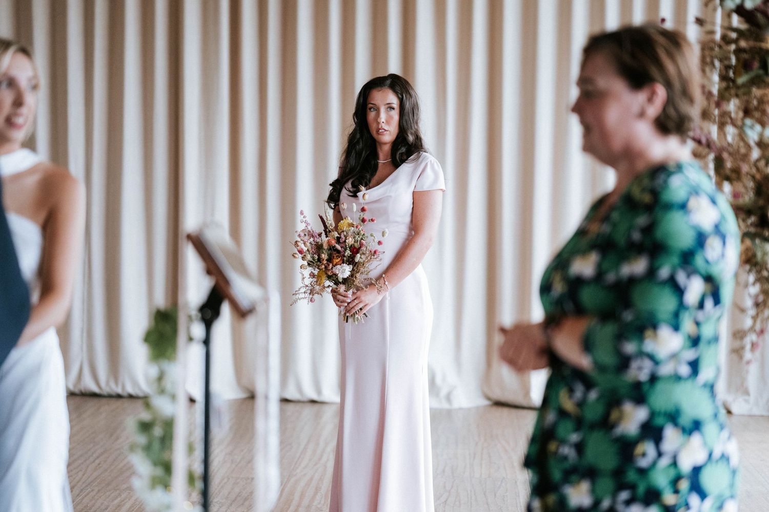 Wedding ceremony attendees in formal attire standing in an indoor venue.
