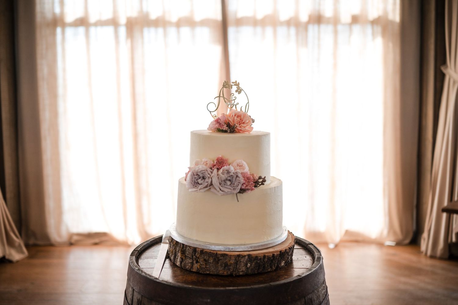 Elegant three-tier white wedding cake with floral decorations on wooden stand.