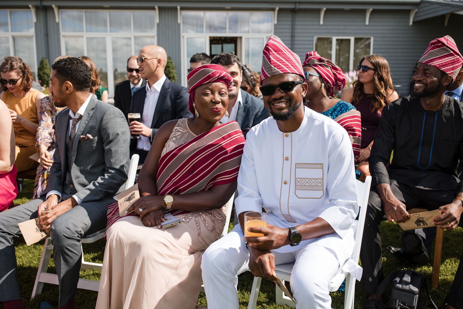 Wedding guests in traditional African attire seated outdoors at a celebration.