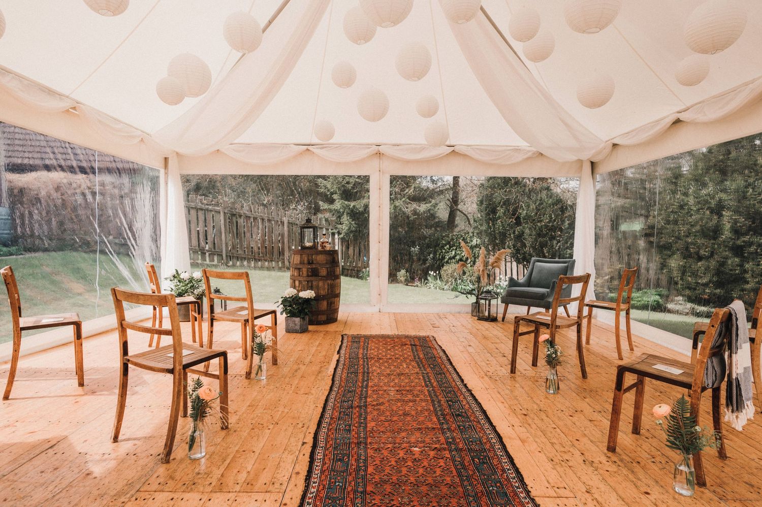 An elegant tent interior with vintage chairs and oriental rug creating an intimate wedding space.