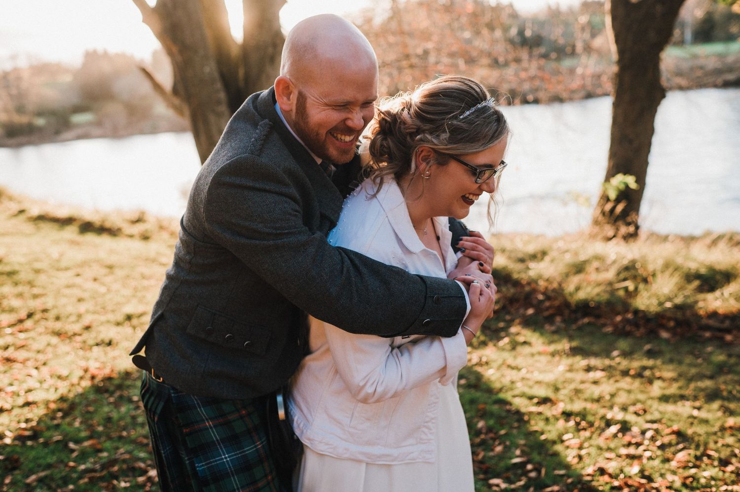 A tender moment captured between newlyweds by a lake during autumn.