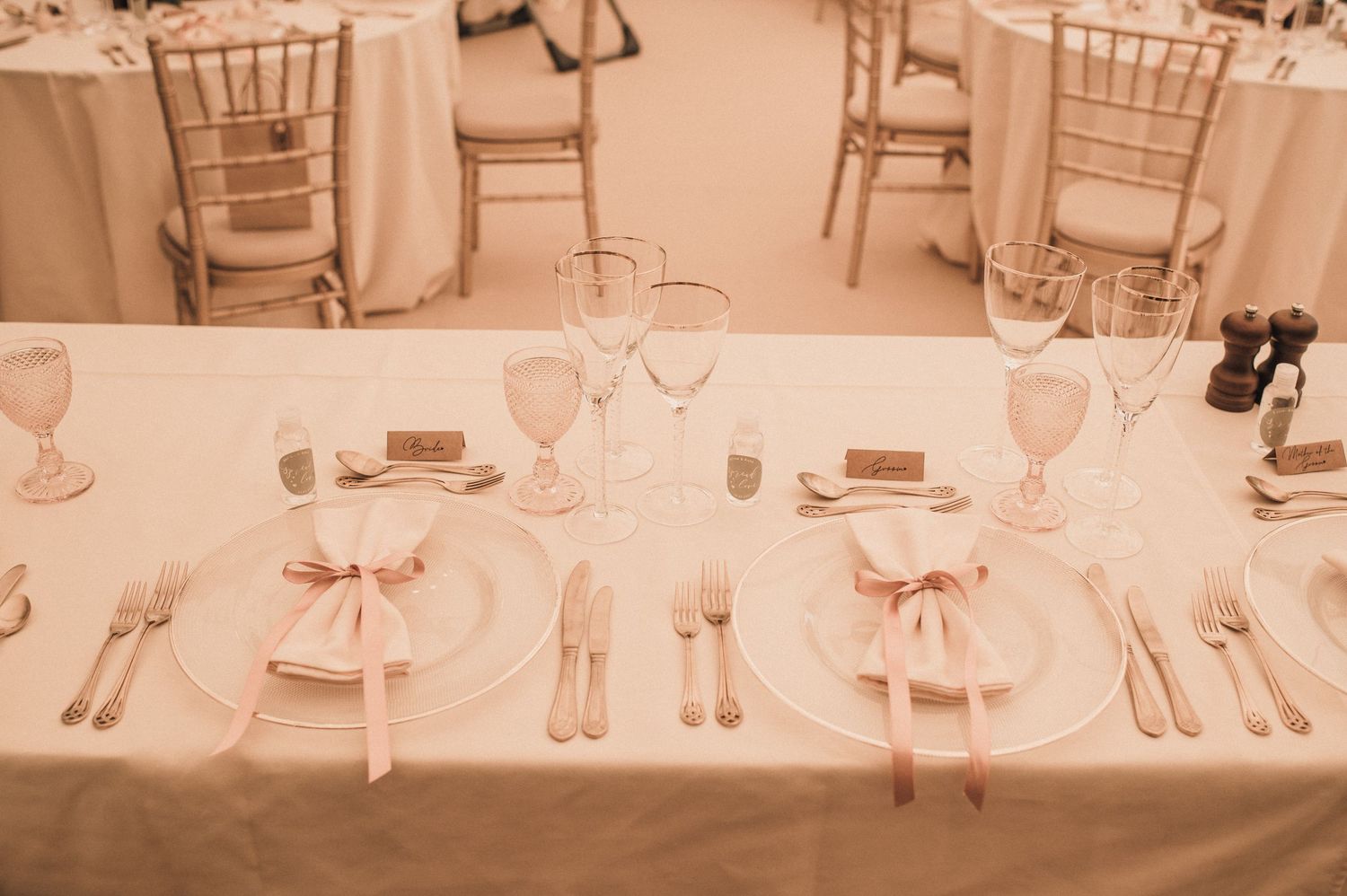 Wedding reception table set with pink napkins, place cards, and chiavari chairs.