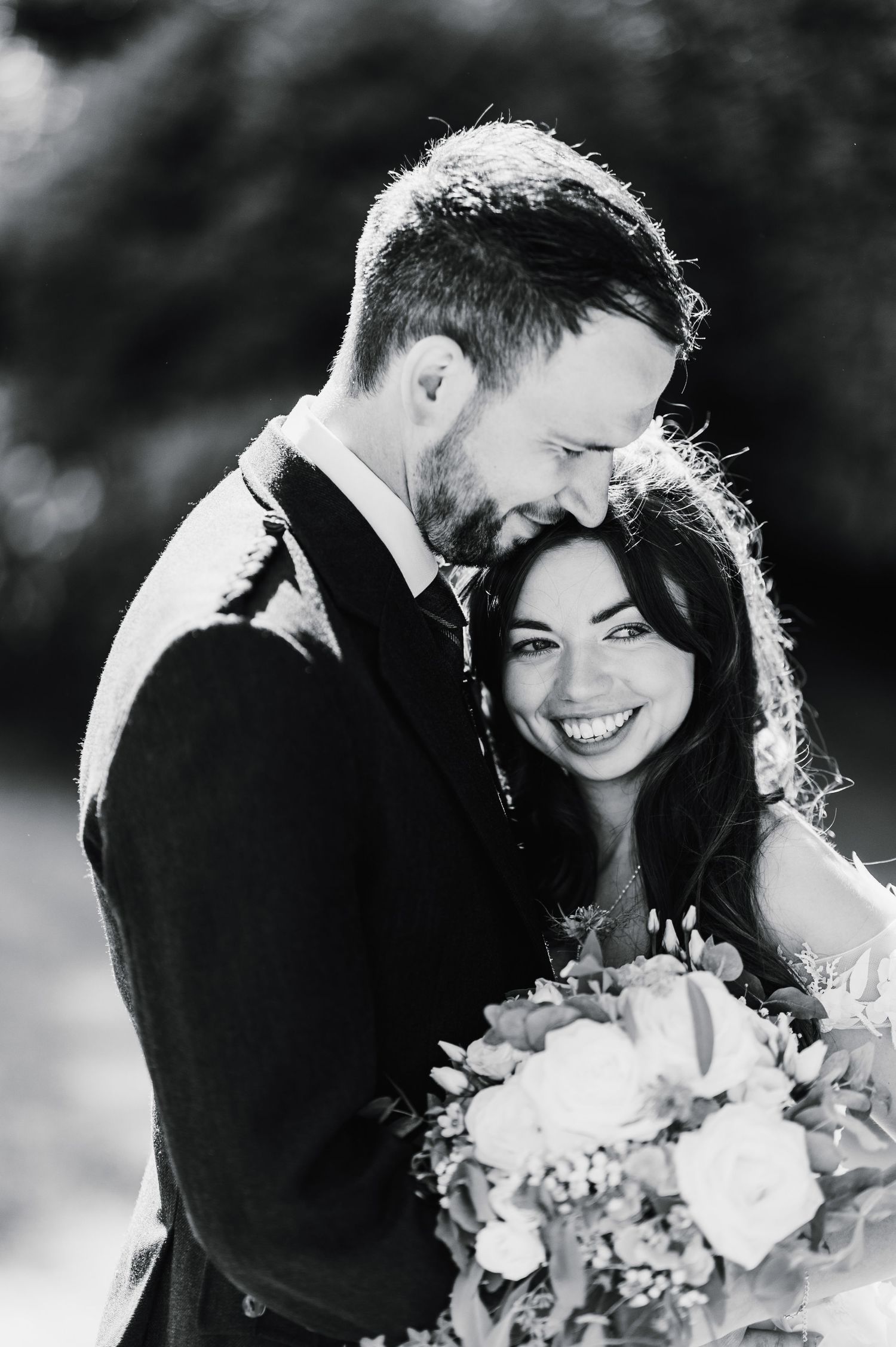 Black and white intimate wedding portrait showing joyful laughter and tender embrace.