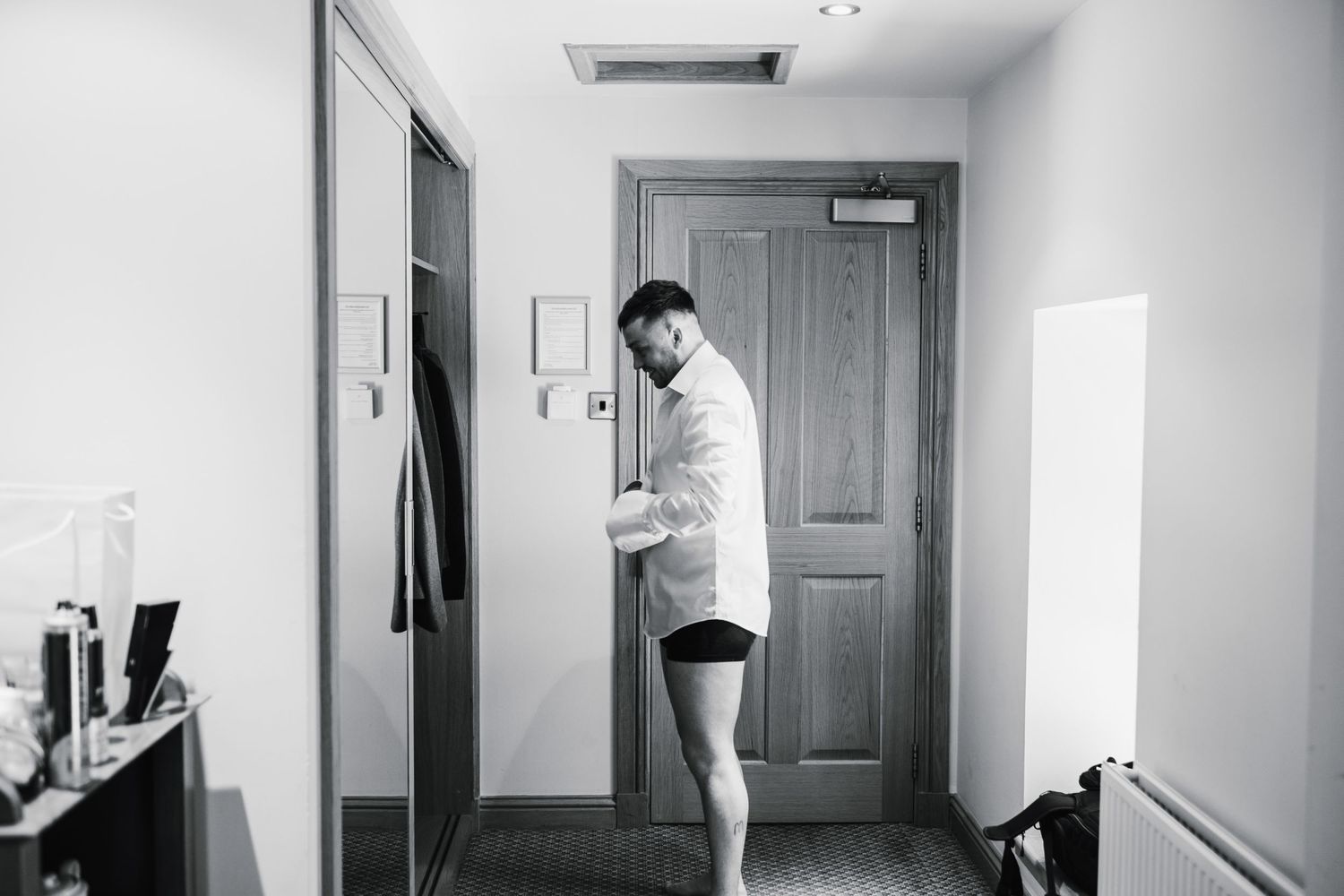 Person getting ready in a hotel room doorway before an event.