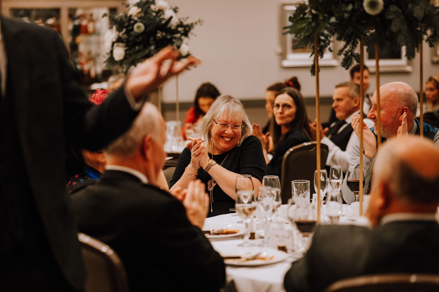 Wedding reception guests sharing joyful moments at an elegantly decorated dinner table.