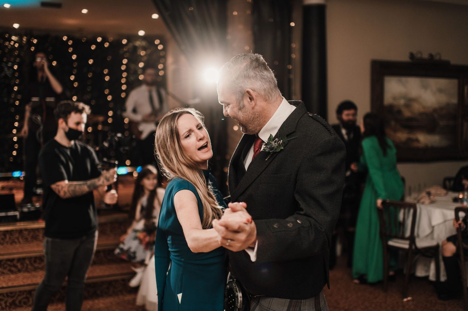 Guests sharing a dance moment at a wedding reception with twinkle lights and elegant decor.