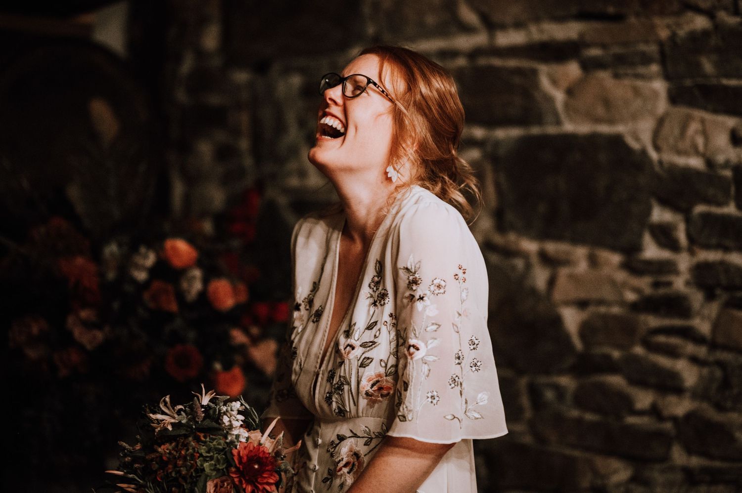 A joyful moment captured in a rustic stone-walled room with floral arrangements.