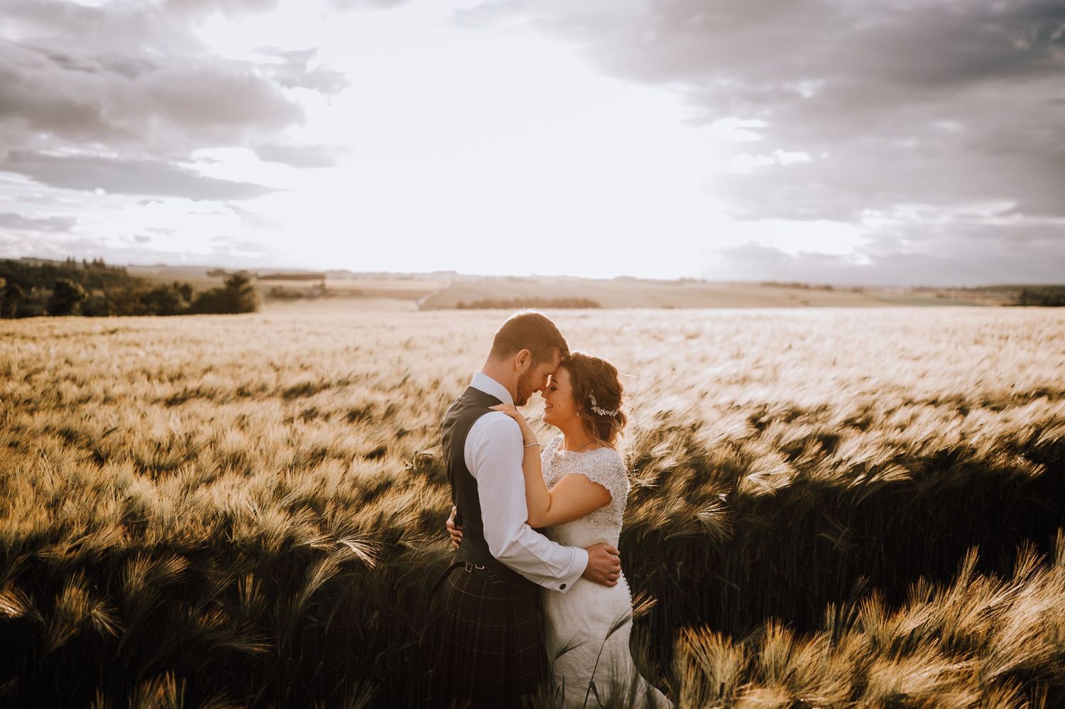 A romantic sunset portrait of newlyweds embracing in a golden wheat field.