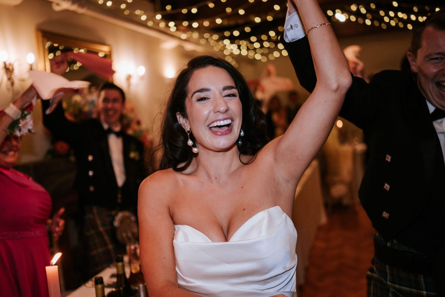 Wedding reception venue decorated with romantic string lights and guests dancing on the dance floor.