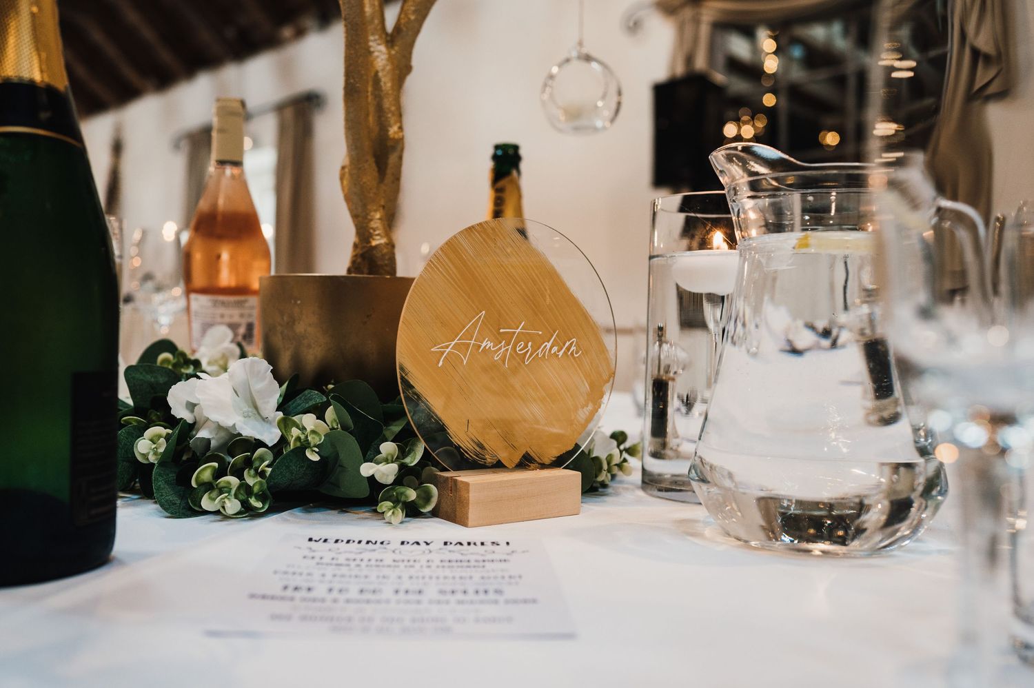 Elegant wedding reception table settings with golden accents, white linens, and decorative floral centerpieces.