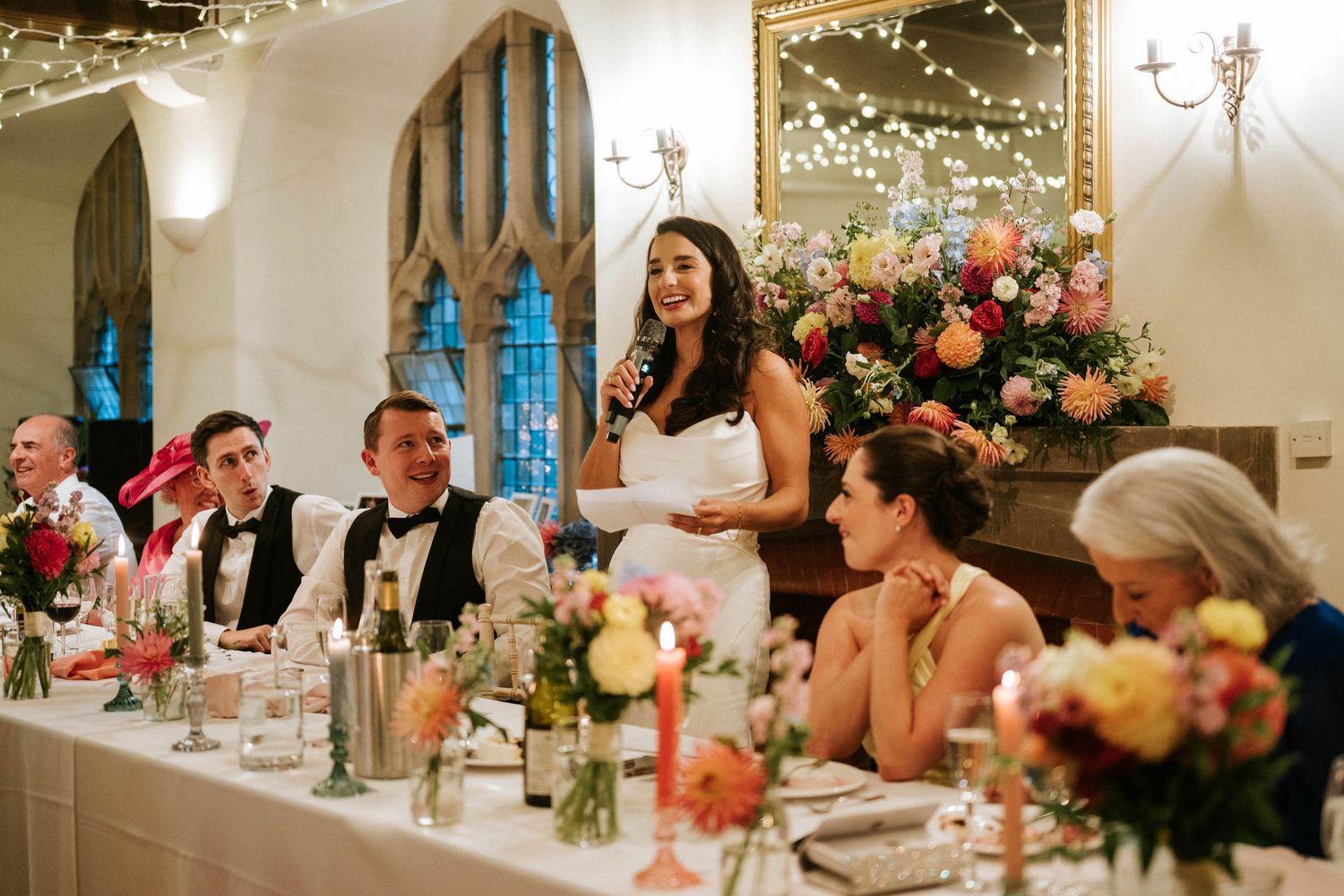 Wedding reception venue decorated with string lights and floral arrangements.