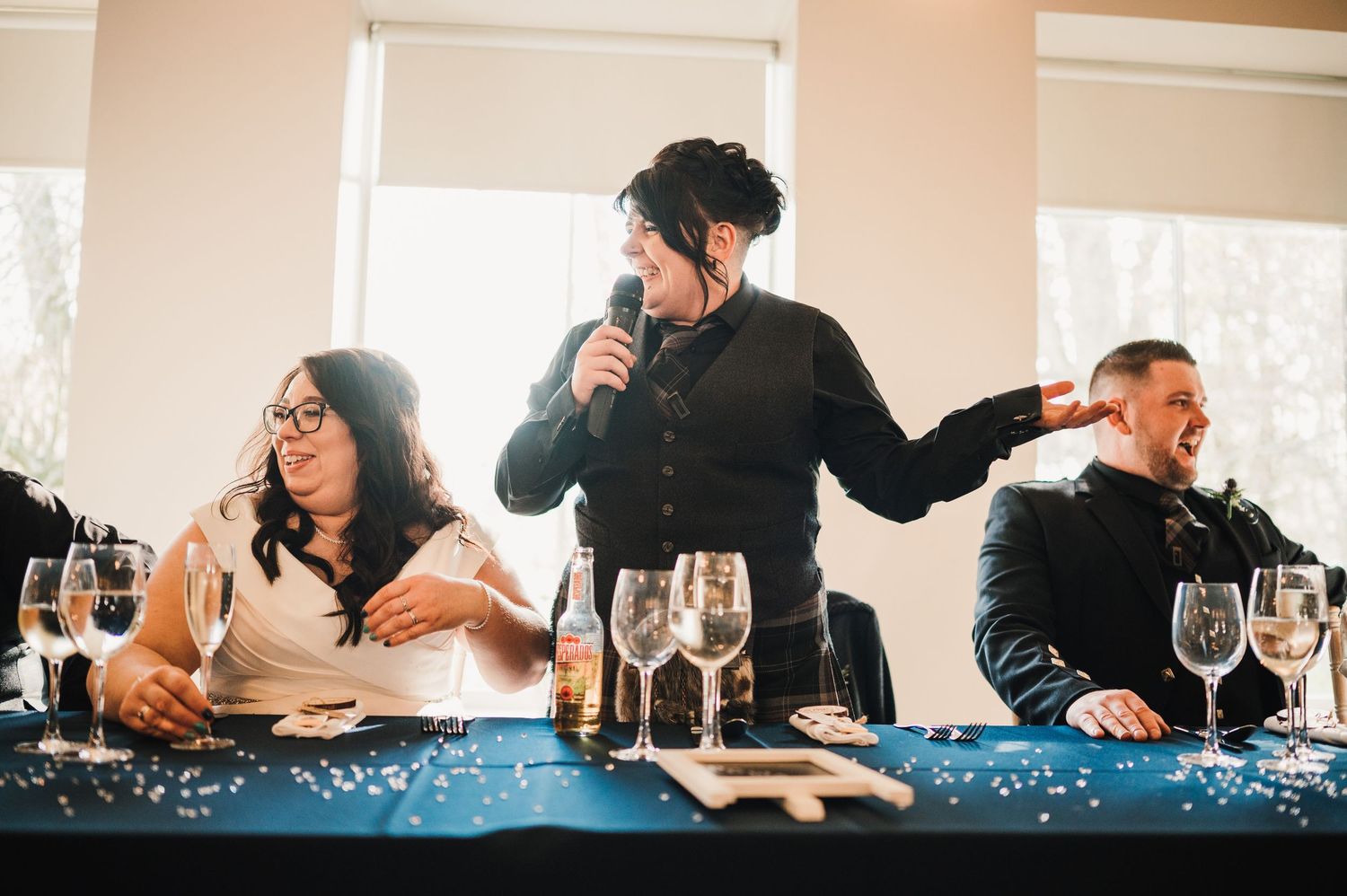 Logie House Wedding Photography. Wedding reception scene with guests and speakers at a decorated table with champagne glasses.