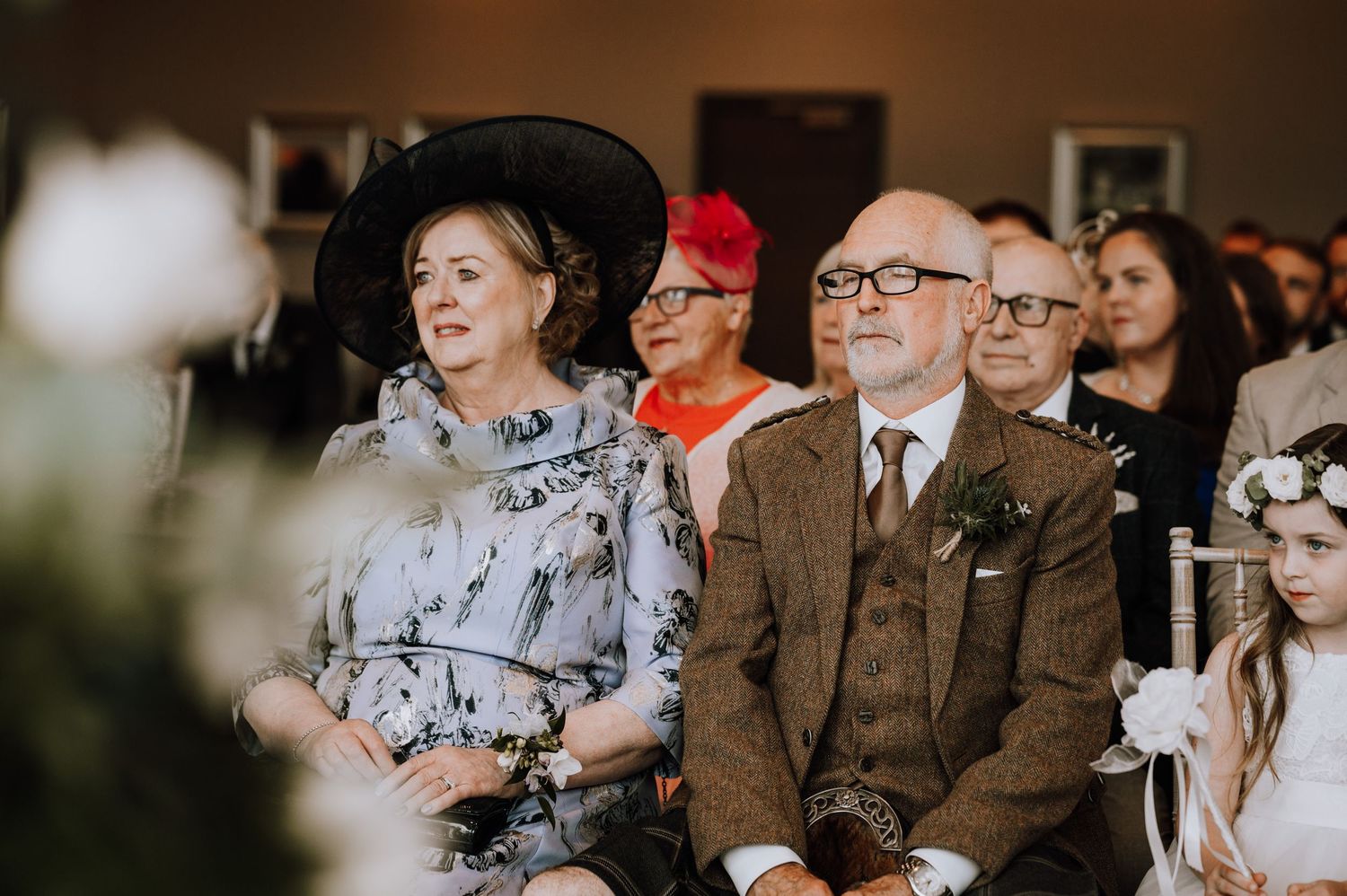 Wedding ceremony guests seated in formal attire watching the proceedings.