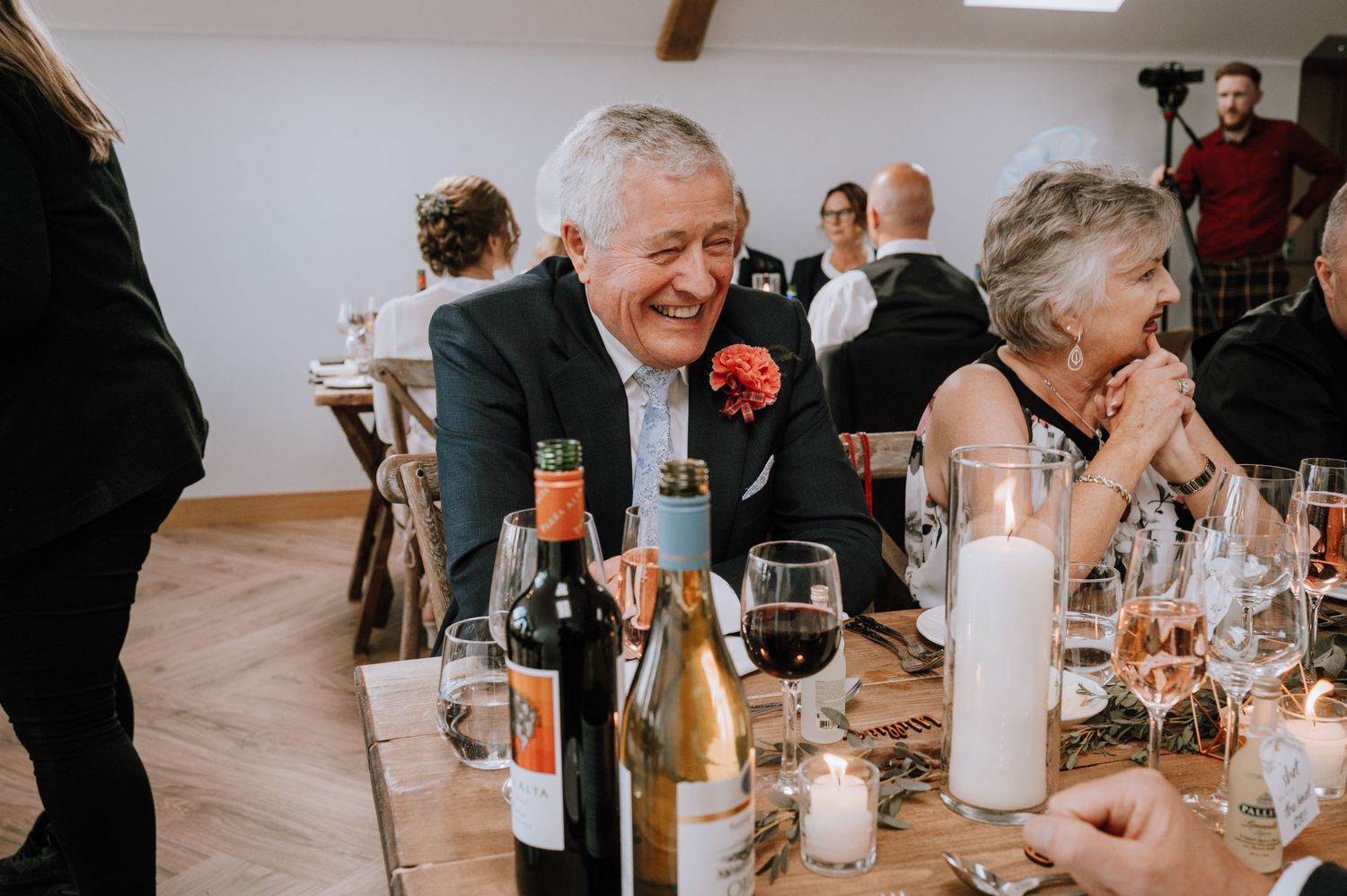 Wedding guests enjoying drinks and conversation at reception dinner table.