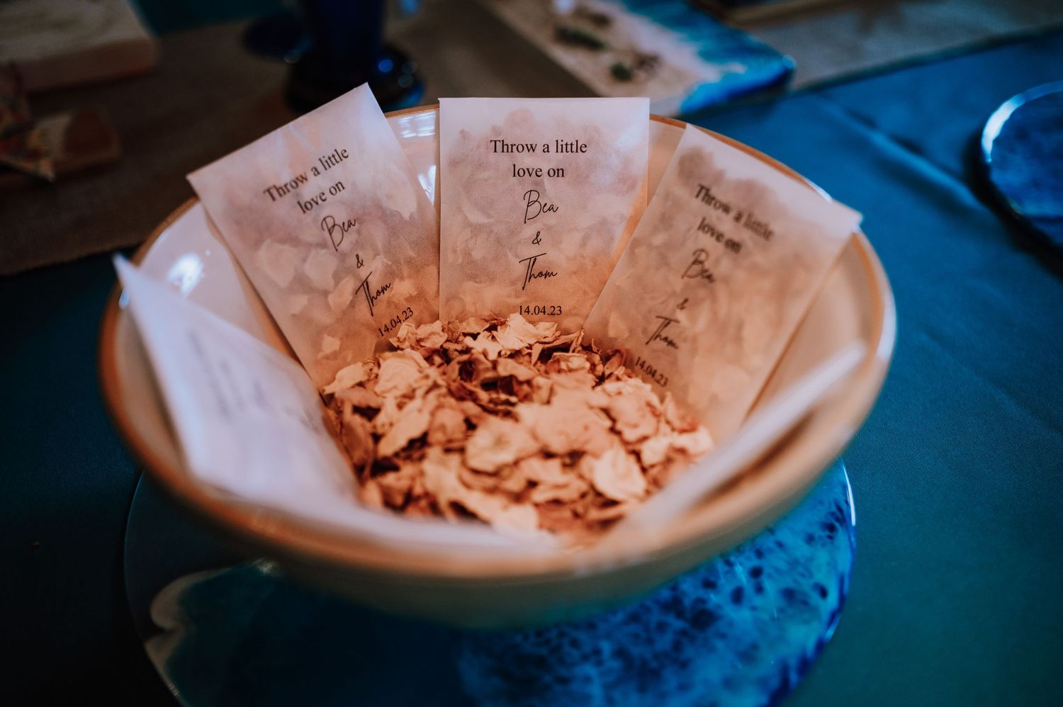 Small paper cones filled with confetti petals sit in a ceramic bowl ready for tossing.