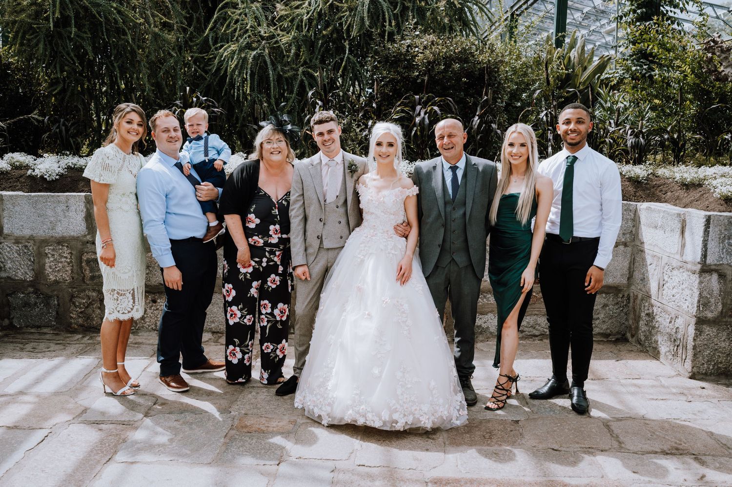 A wedding party lined up for a formal photo on stone pavement.