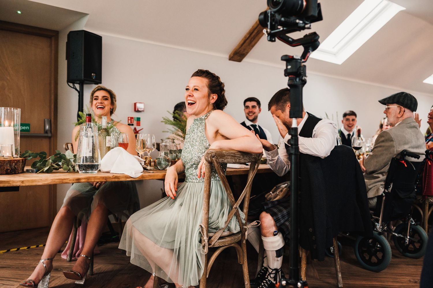 Wedding reception guests laugh and enjoy entertainment in an elegant venue with skylights.