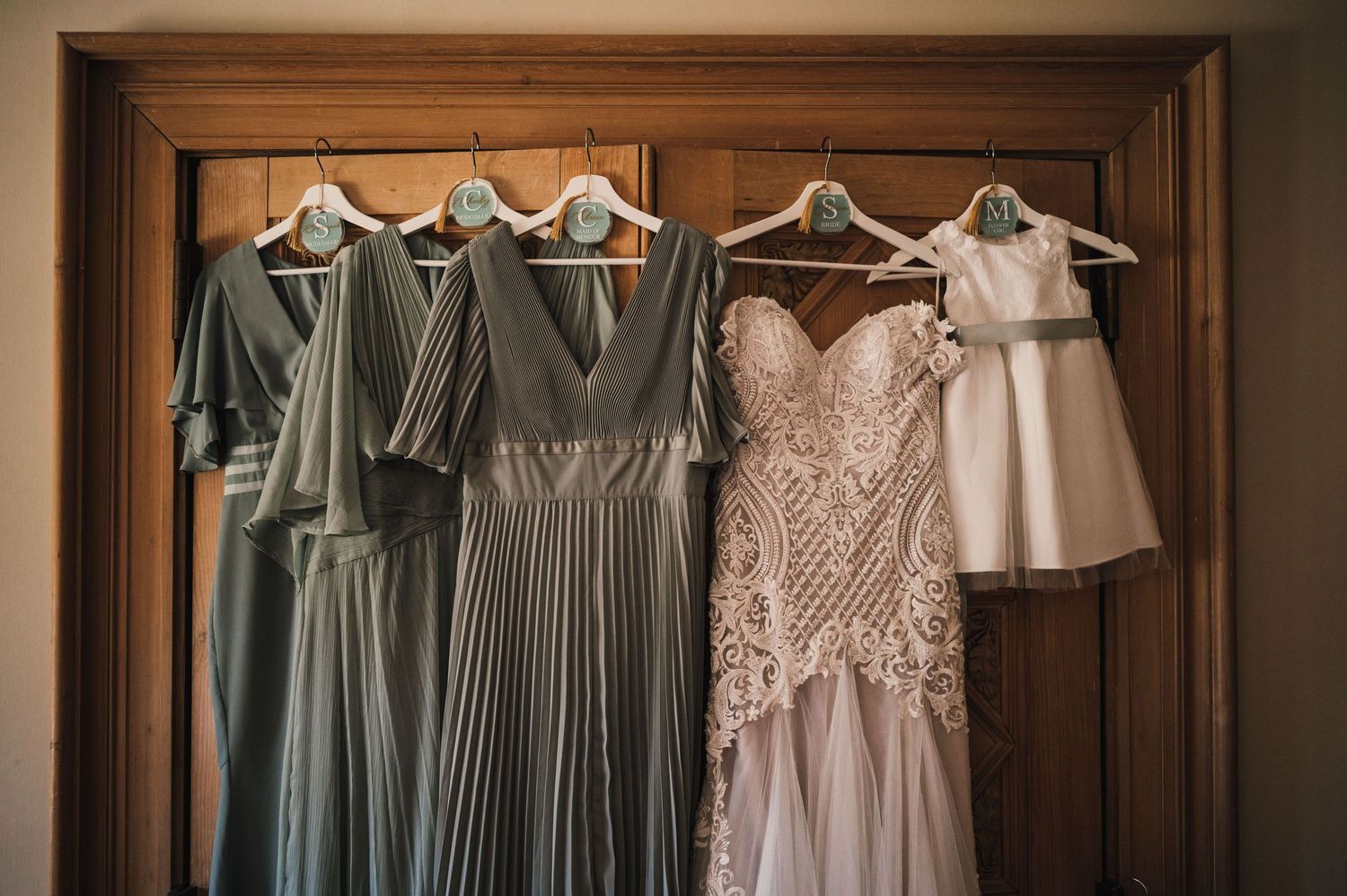 Wedding dresses and bridesmaid gowns hanging in dusty blue and blush tones.
