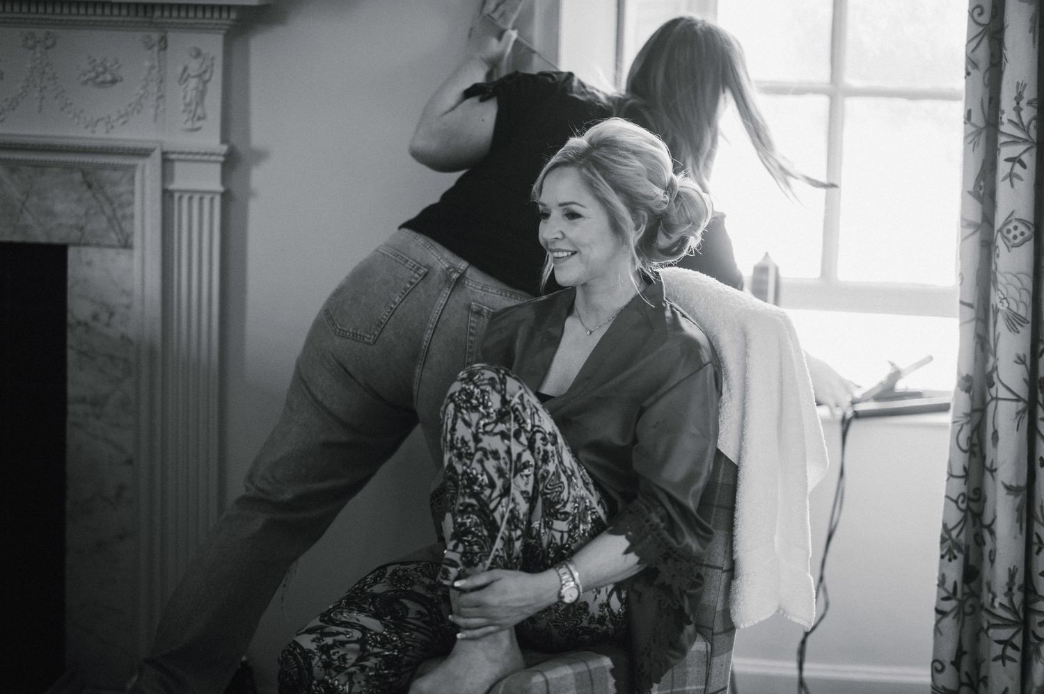 Black and white image of person in robe getting ready by window.