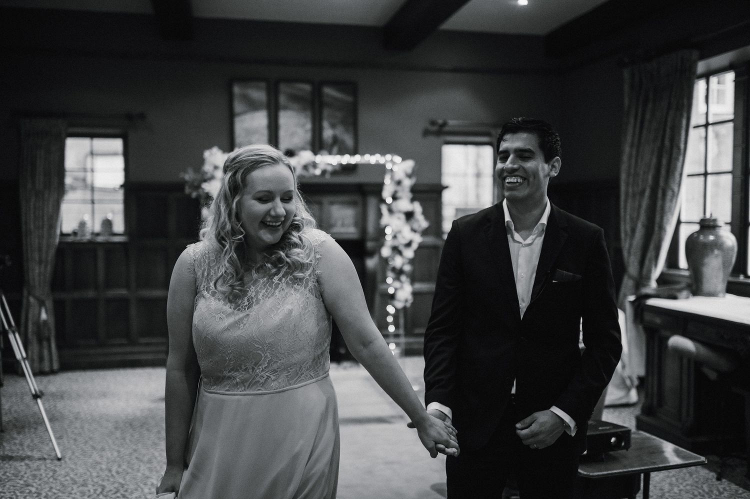 A couple shares a joyful moment during their wedding ceremony in a decorated indoor venue.