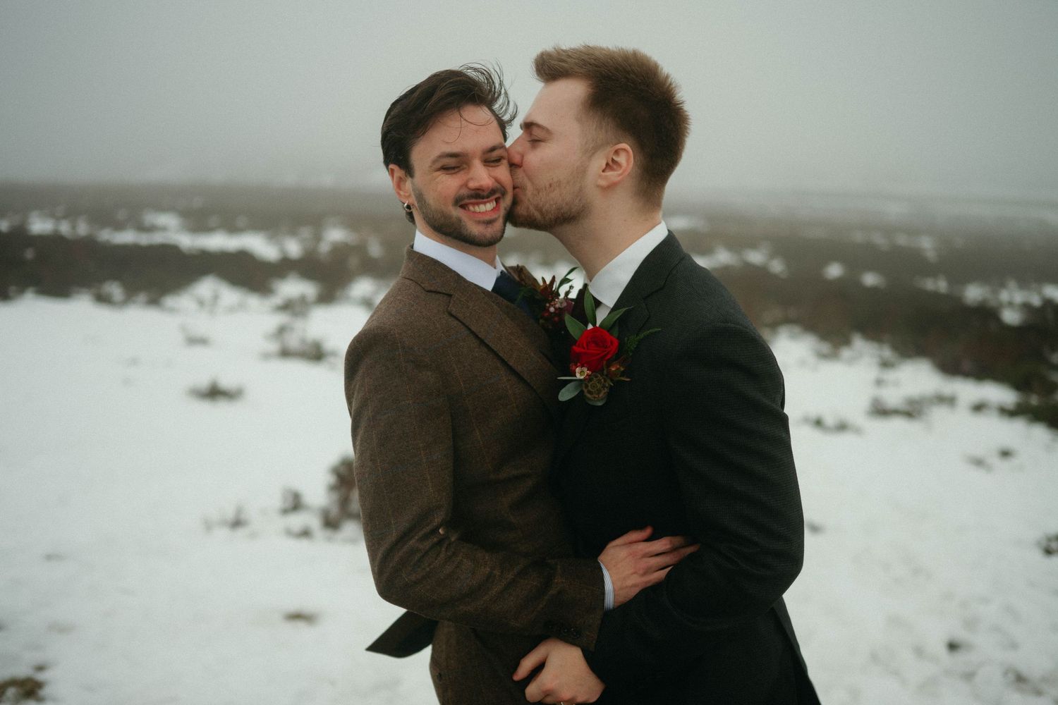A romantic winter engagement photoshoot with a couple embracing in a snowy landscape at sunset.
