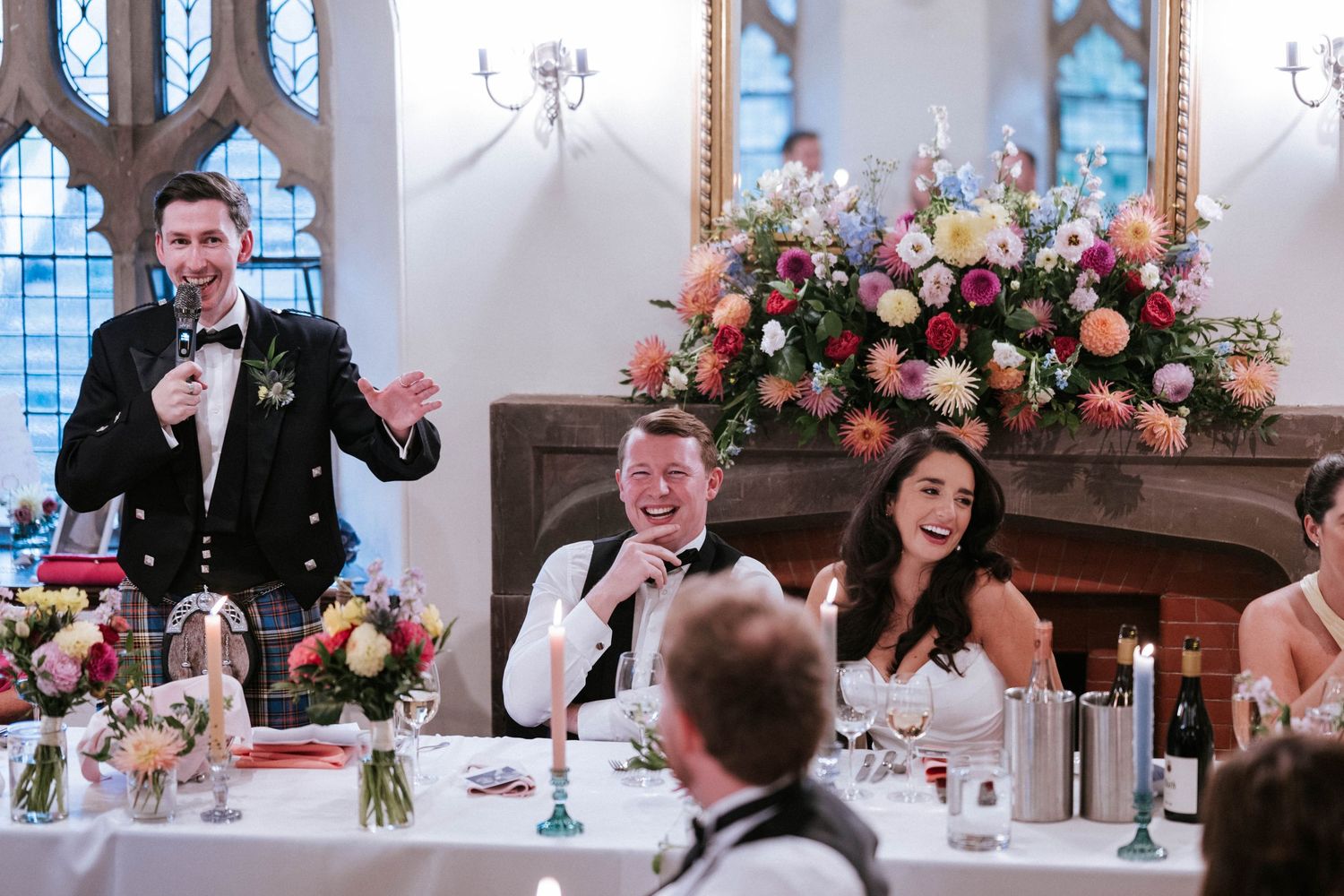 Wedding reception celebration with ornate windows and pink floral arrangements.