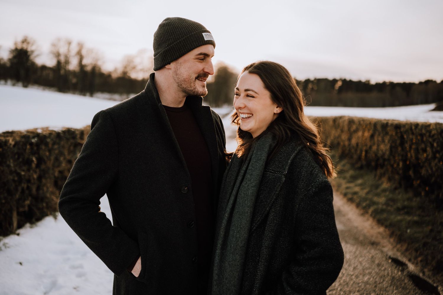 A couple shares a romantic moment in a snowy winter landscape during their engagement photoshoot.