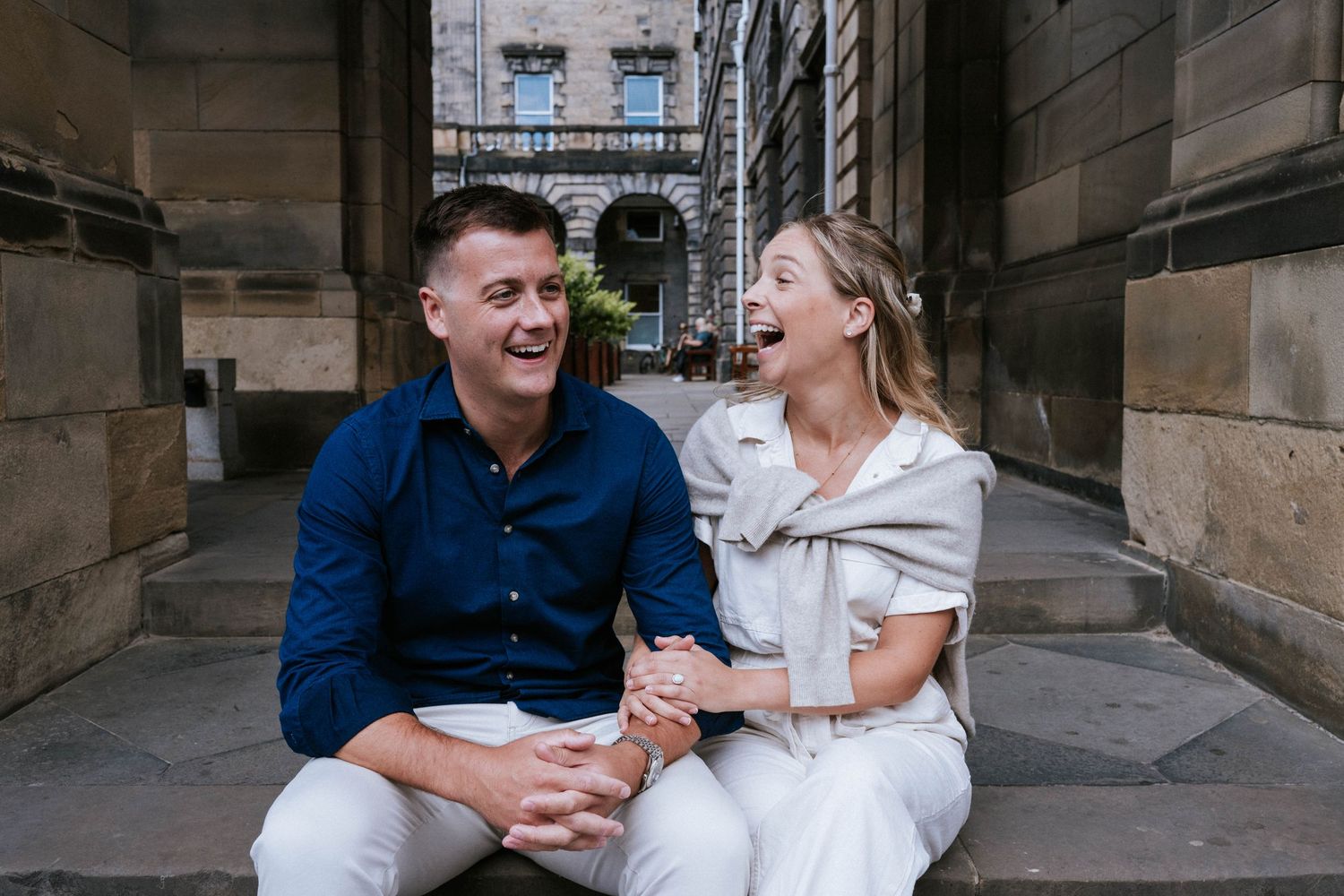 Engagement photography session Aberdeen. Couple shares joyful moment together in front of stone archway architecture.
