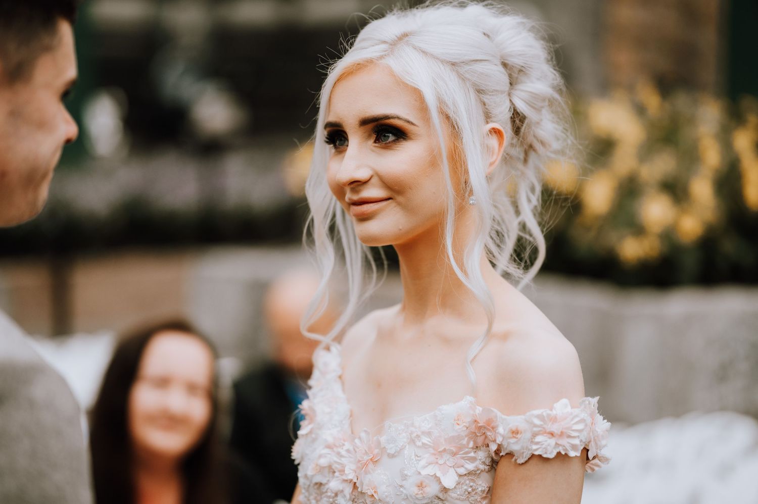 A bride in a delicate off-shoulder wedding gown with romantic floral details.