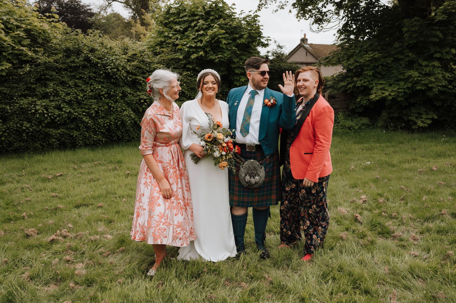 Family members gather around newlyweds for outdoor wedding portrait.