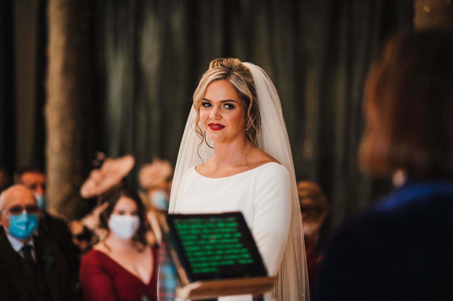 A ceremony in an elegant ballroom with dark curtains and digital tablets for readings.