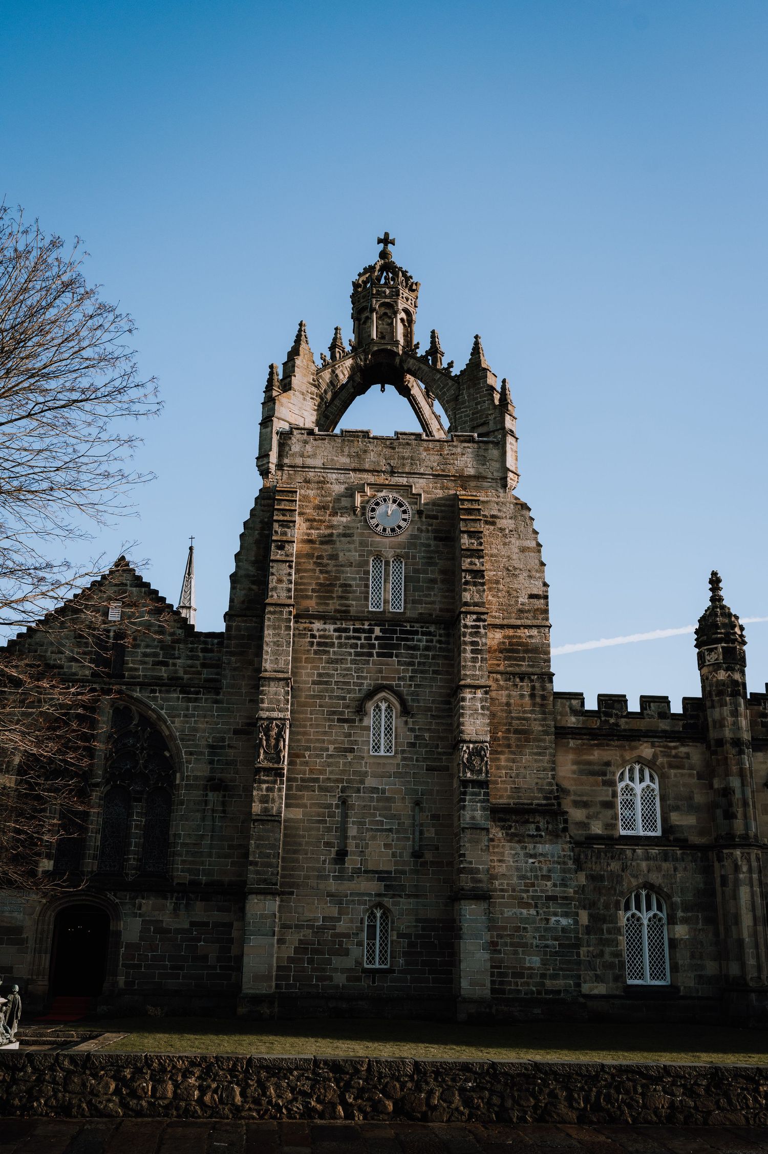 Historic Gothic stone church tower with ornate architectural details against clear blue sky.