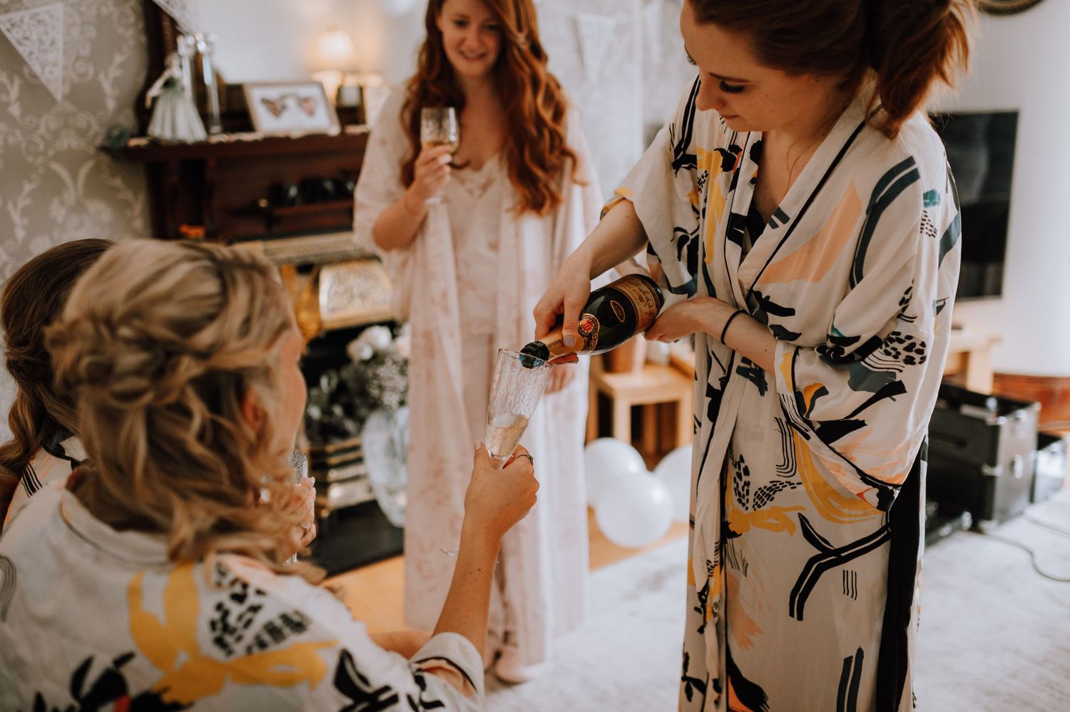 Wedding morning preparations in a room with floral wallpaper and natural light.