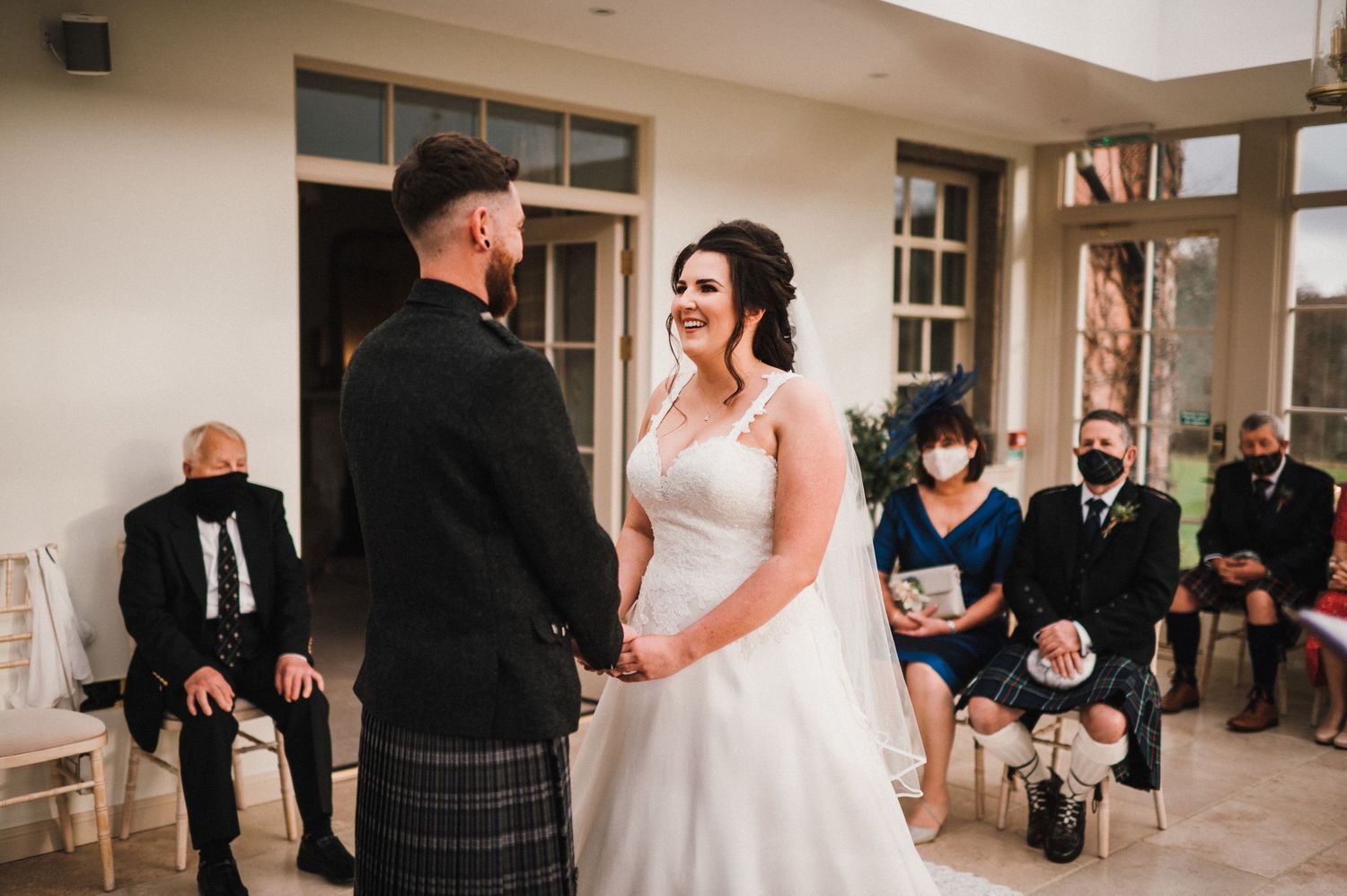 An intimate wedding ceremony with Scottish elements takes place in a light-filled indoor venue.
