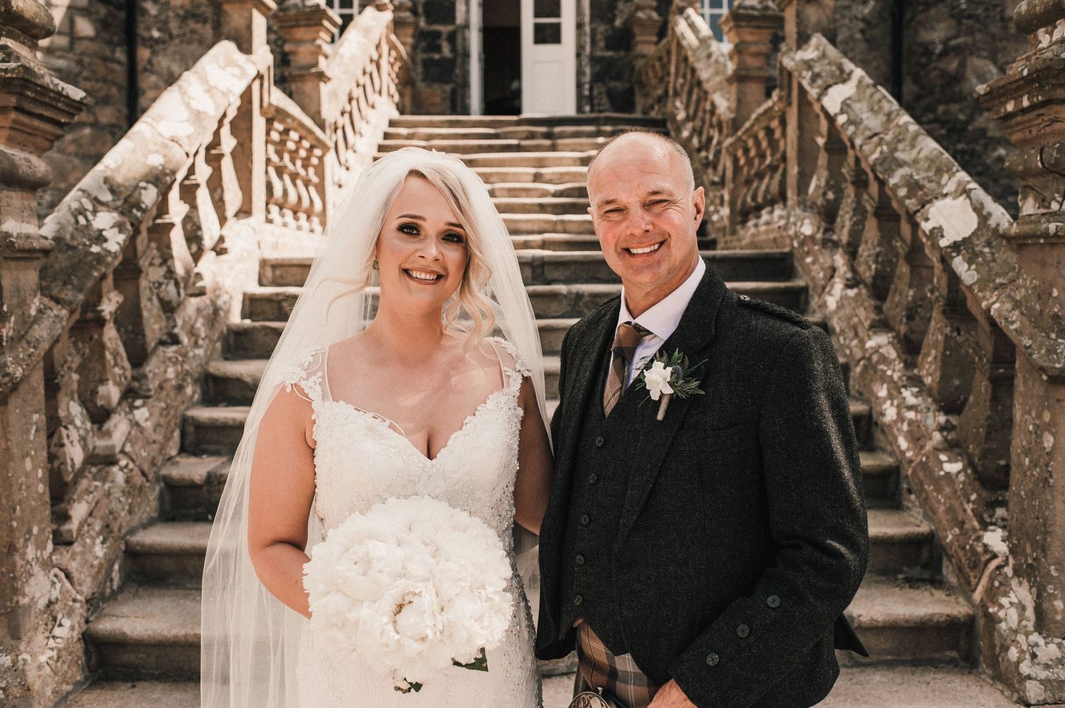 A trio stands together on ornate stone steps for a formal wedding portrait.