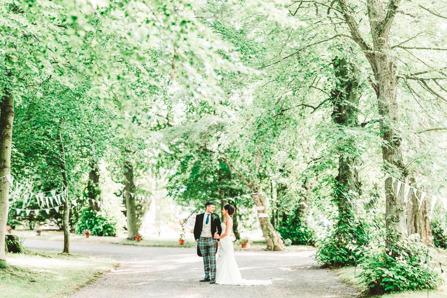 A sunlit garden path with lush greenery creates a romantic wedding photo backdrop.