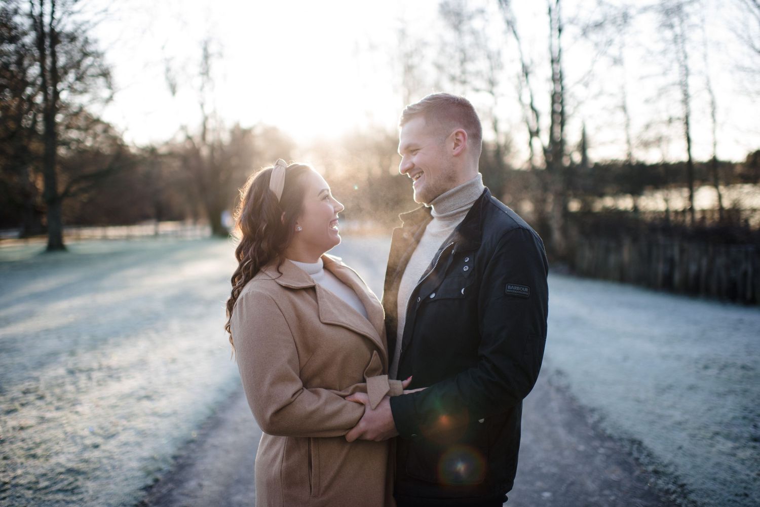 A romantic couple shares an intimate moment on a frosty path during golden hour.