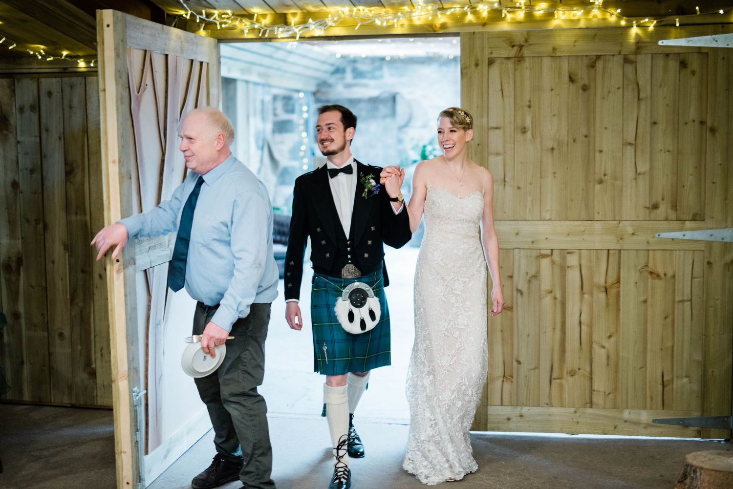 A wedding celebration in a rustic wooden venue decorated with string lights.