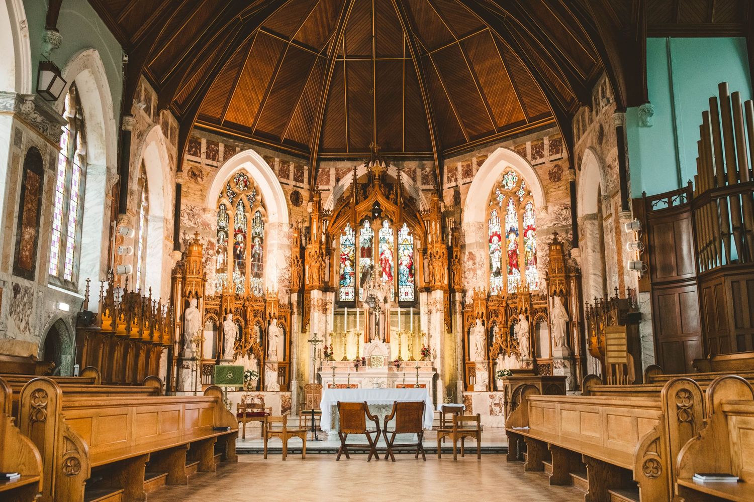 Interior of a beautiful Gothic church with ornate altar and wooden pews.