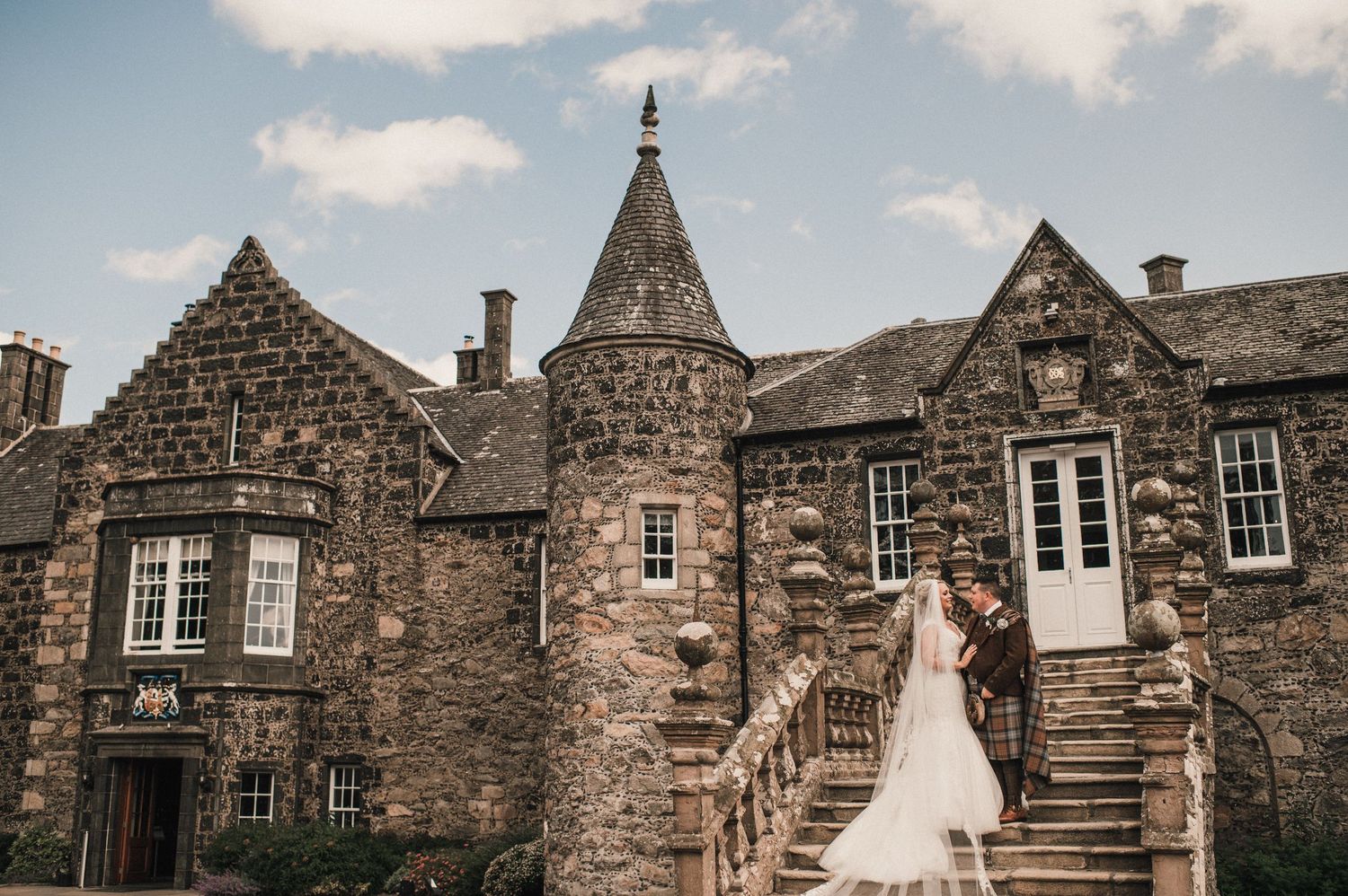 Stone castle wedding venue with historic architecture and grand staircase in moody overcast lighting.