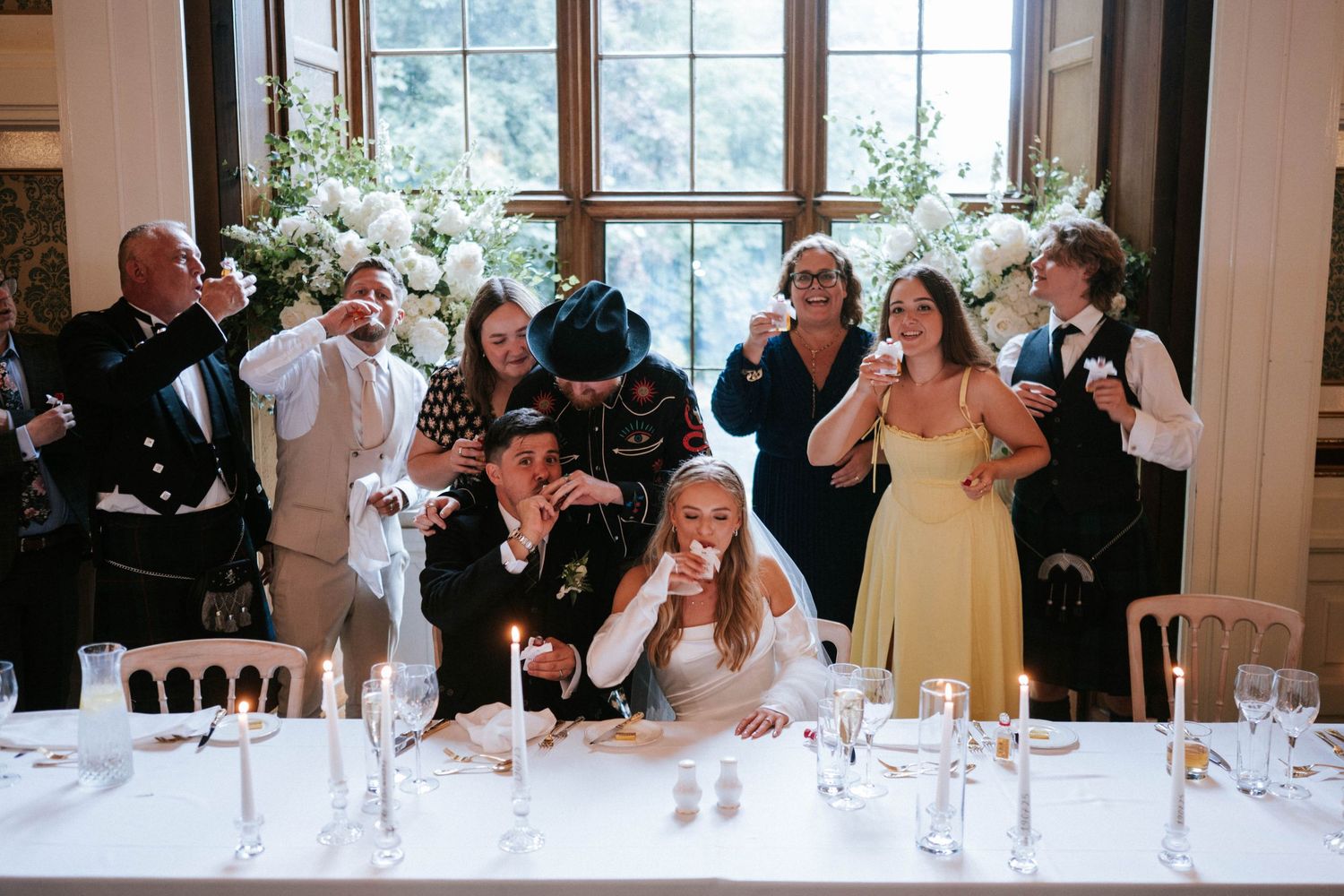 Wedding reception guests participate in a napkin-waving tradition in an elegant dining room.