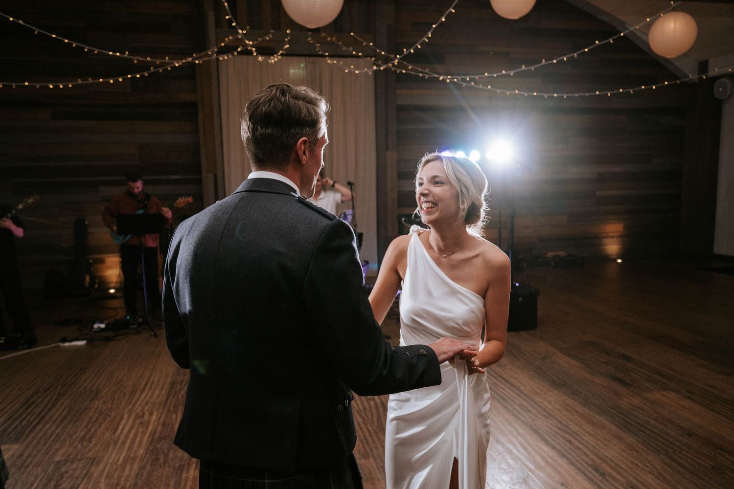 Wedding dance floor with romantic string lights and couples dancing in dim lighting.