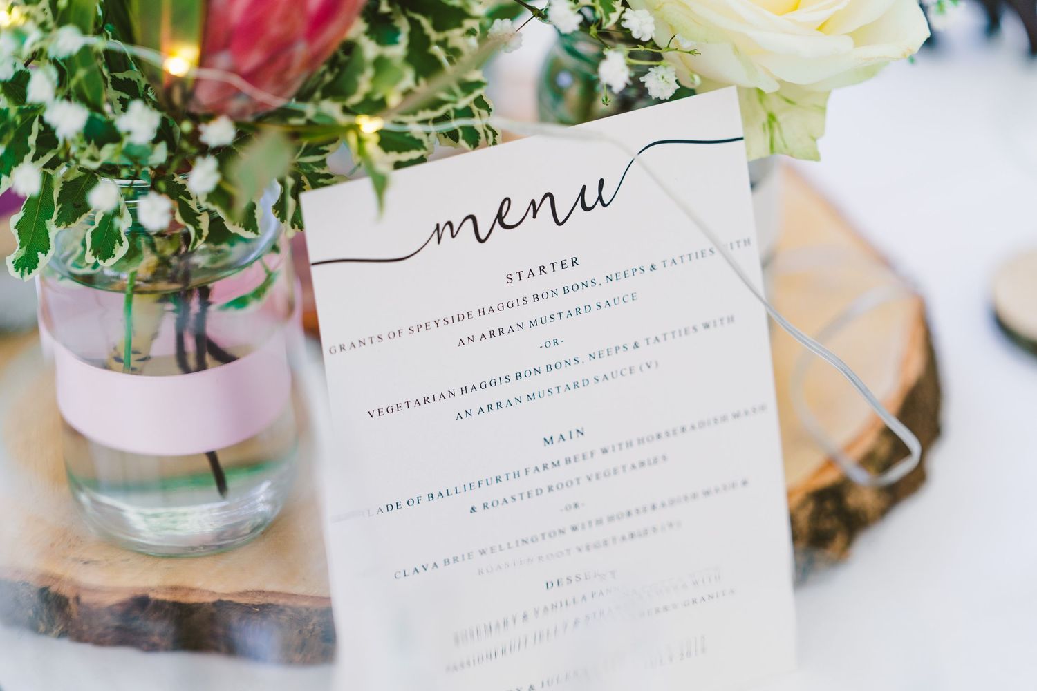 Wedding reception table settings with floral centerpieces and elegant menu cards.