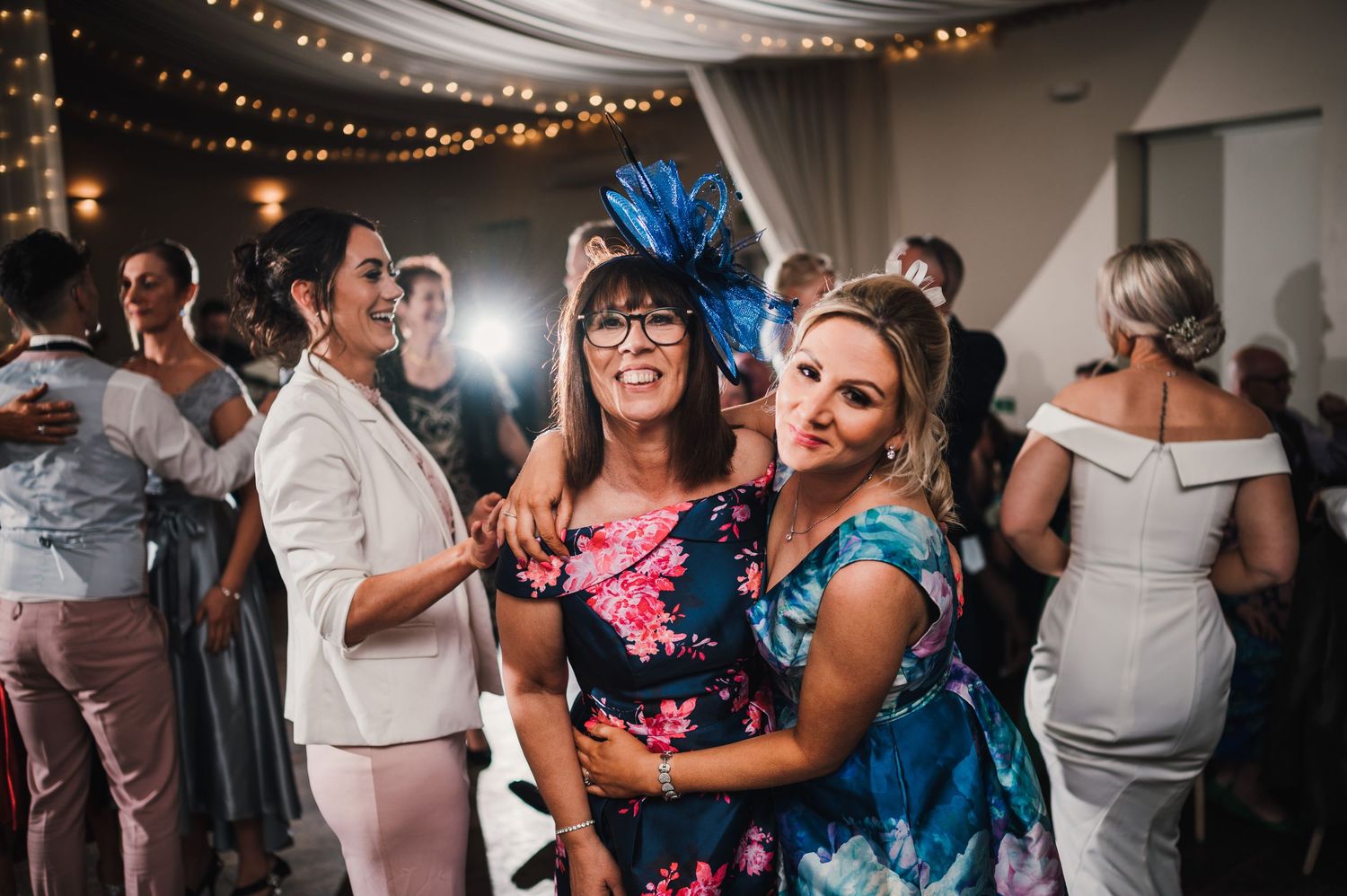 Logie House Wedding Photography. Lively dance party at wedding reception with guests enjoying themselves under decorative lighting.