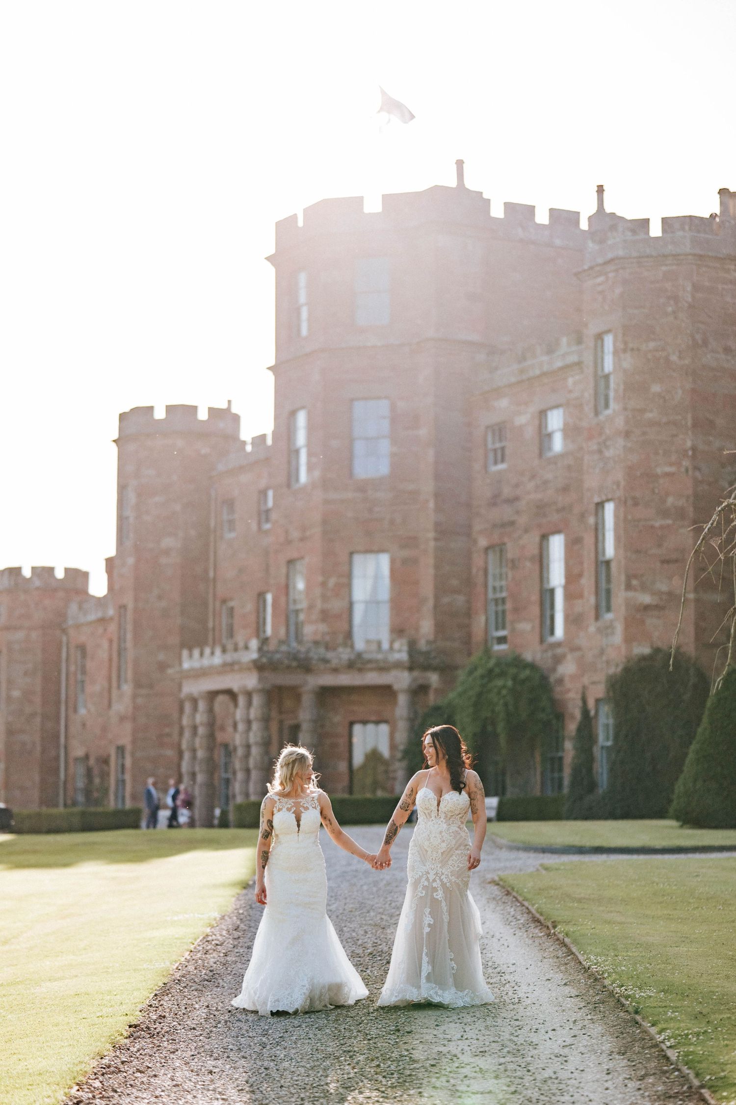 Aberdeen Wedding Photography. Wedding couple walking along path in front of grand historic castle building at sunset.