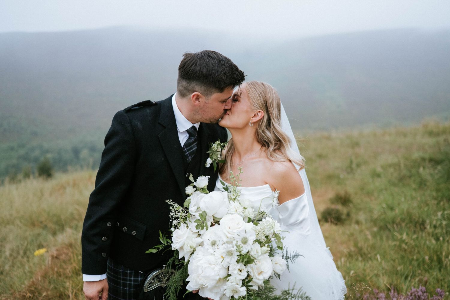 Scenic outdoor wedding photography session in misty rolling hills with white floral bouquet.