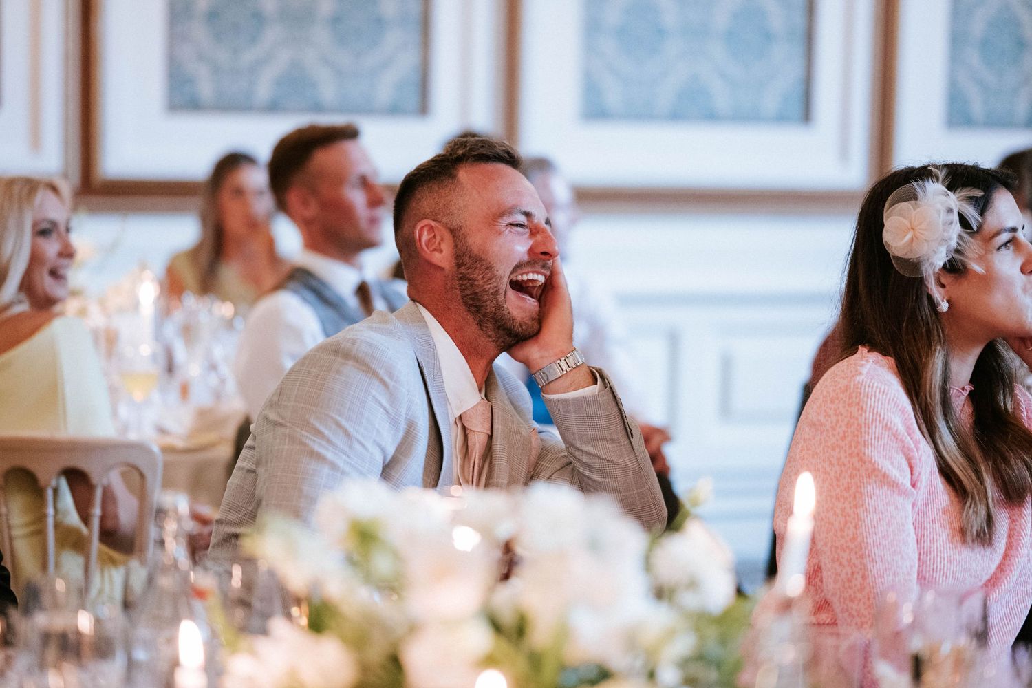 Wedding reception guests laugh and celebrate during an indoor evening celebration.