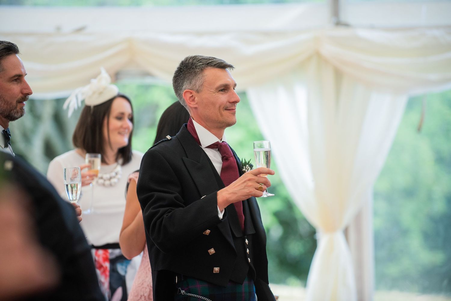 Wedding reception guests enjoy celebrations under an elegant white tent.