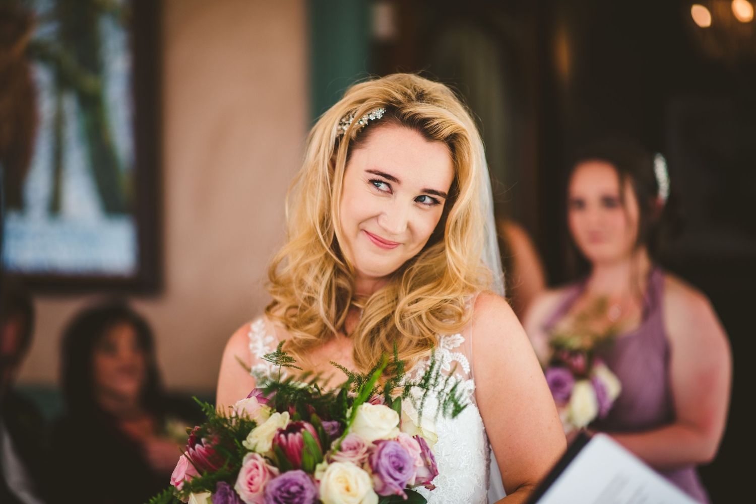 A wedding reception celebration inside a warmly lit venue with decorative lighting.