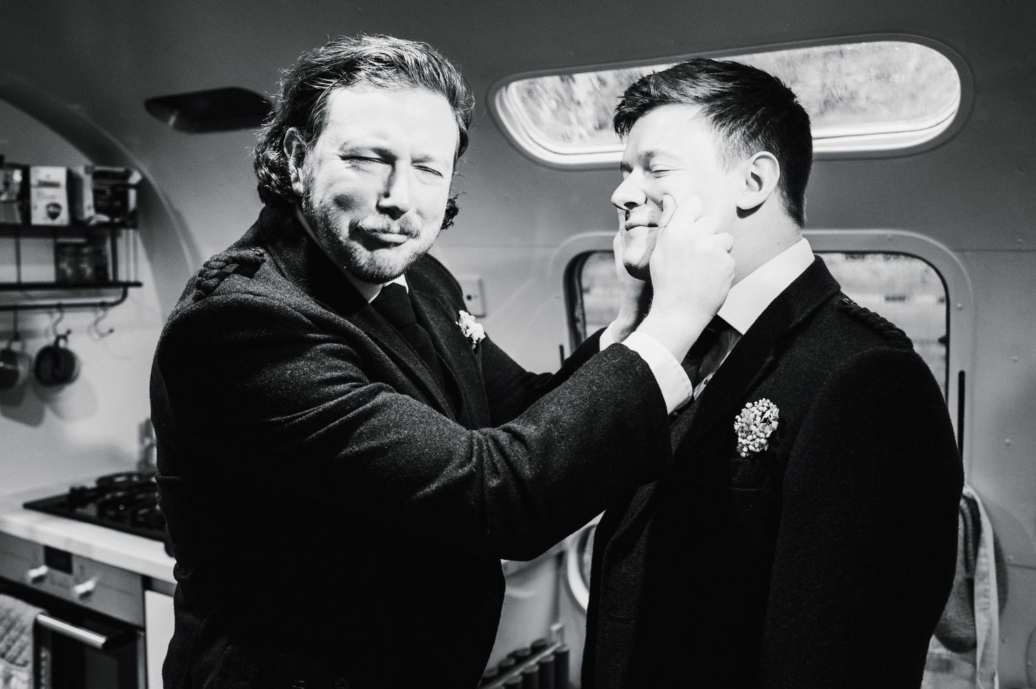 A candid black and white moment showing two people interacting in what appears to be getting ready preparations.